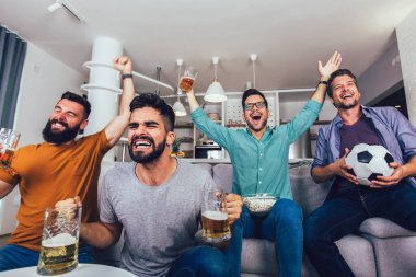 Çok heyecanlı arkadaşlar evde, içeride futbol maçı izleyerek eğleniyorlar. Arkadaşlık, eğlence, spor, dinlenme, ev partisi konsepti