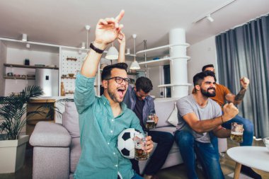 Çok heyecanlı arkadaşlar evde, içeride futbol maçı izleyerek eğleniyorlar. Arkadaşlık, eğlence, spor, dinlenme, ev partisi konsepti