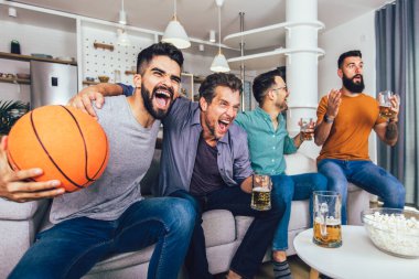 Mutlu arkadaşlar ya da basketbol taraftarları televizyonda basketbol maçı izleyip zaferi evde kutluyorlar..