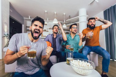 Mutlu arkadaşlar ya da basketbol taraftarları televizyonda basketbol maçı izleyip zaferi evde kutluyorlar..