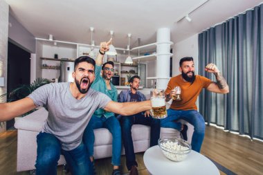 Çok heyecanlı arkadaşlar evde, içeride futbol maçı izleyerek eğleniyorlar. Arkadaşlık, eğlence, spor, dinlenme, ev partisi konsepti