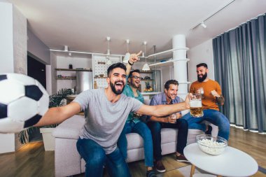 Çok heyecanlı arkadaşlar evde, içeride futbol maçı izleyerek eğleniyorlar. Arkadaşlık, eğlence, spor, dinlenme, ev partisi konsepti