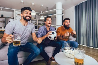 Çok heyecanlı arkadaşlar evde, içeride futbol maçı izleyerek eğleniyorlar. Arkadaşlık, eğlence, spor, dinlenme, ev partisi konsepti