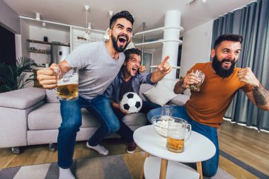 Çok heyecanlı arkadaşlar evde, içeride futbol maçı izleyerek eğleniyorlar. Arkadaşlık, eğlence, spor, dinlenme, ev partisi konsepti