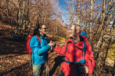 Doğada yürüyüş yapan, orman yolunda yürüyen ve konuşan iki gezgin birlikte sıcak çay içiyorlar..