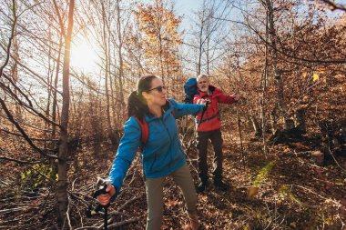 Doğada yürüyüş yapan, orman yolunda yürüyen ve konuşan iki gezgin.