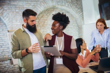 Ofiste dikilirken dijital tablet kullanan mutlu iş arkadaşları