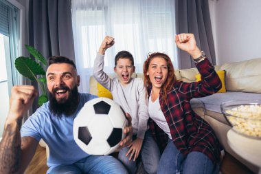 Taraftarların ailesi evde futbol maçı izliyor.