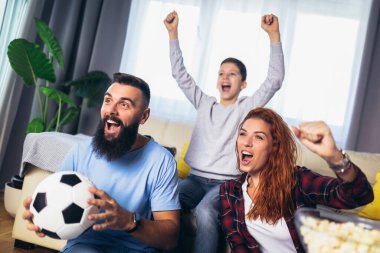 Taraftarların ailesi evde futbol maçı izliyor.