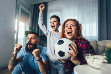 Taraftarların ailesi evde futbol maçı izliyor.