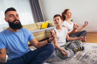 Sağlıklı bir sabah esnemesi. Anne ve baba ve oğlu evde jimnastik yapıyor.