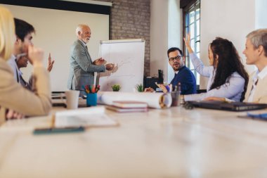 İşletme atölyesi sözcüsü ofisteki meslektaşlarına pozitif iş büyümesi hakkında bir sunum yapıyor..