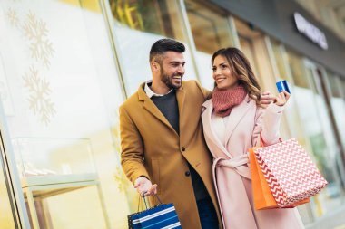 Kredi kartıyla alışveriş yapan genç ve mutlu bir çift.