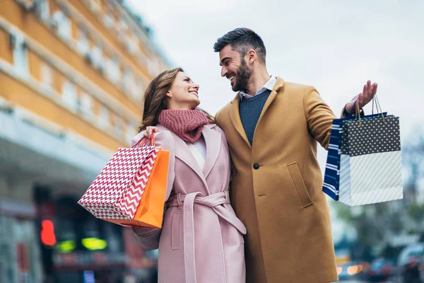 買い物の後の笑顔のカップル歩く — ストック写真