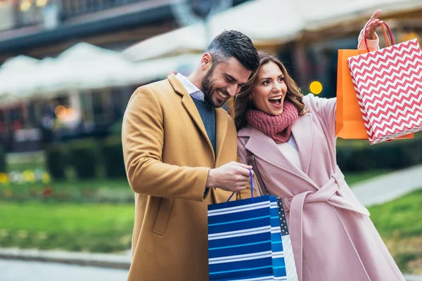 買い物の後に歩いて買い物袋を見て微笑むカップル — ストック写真