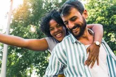 Park yerinde genç bir coupe. Erkek arkadaşı kız arkadaşını sırtında taşıyor..