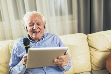 Kıdemli adam mikrofon kullanıyor ve karaoke söylüyor.