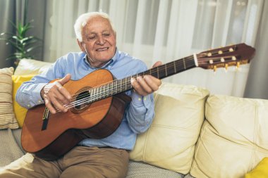 Son sınıf öğrencisi oturma odasında gitar çalıyor.