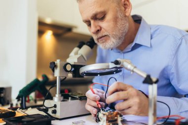 Mühendis bozuk bilgisayar ekipmanlarını tamir ediyor. Elektronik tamir atölyesi, teknoloji geliştirme konsepti