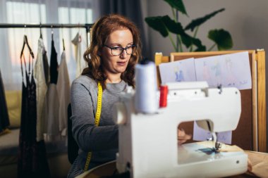 Evinde çalışırken dikiş dikebilen neşeli genç bir kadın.