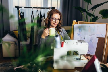 Evinde çalışırken dikiş dikebilen neşeli genç bir kadın.