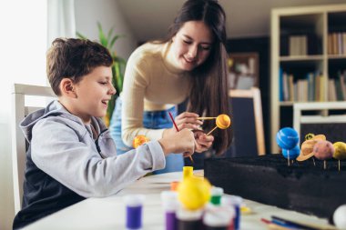 Mutlu okul çocuğu ve kız evde bir okul fen projesi için güneş sistemi yapıyorlar.