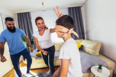 Aile evde saklambaç oynuyor, mutlu çocuk anne ve babayla eğleniyor..