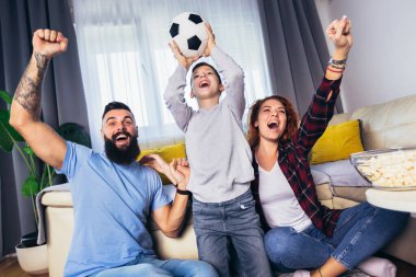Taraftarların ailesi evde futbol maçı izliyor.