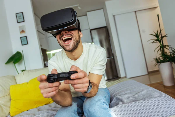 Oturma odasında sanal gerçeklik gözlüğü takan ve video oyunu oynayan bir adam..