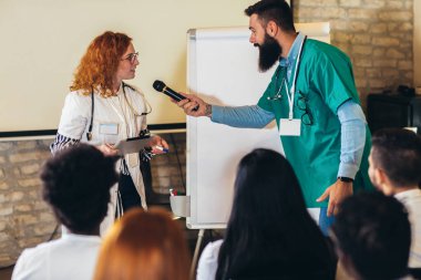 Konferans merkezinde bir grup sağlık çalışanı ve iş adamına seminer veren doktor..