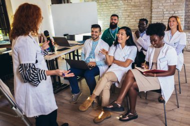 Konferans merkezinde bir grup sağlık çalışanı ve iş adamına seminer veren doktor..