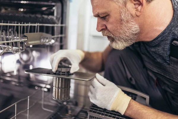 Portrait Of Male Technician Repairing Dishwasher In Kitchen