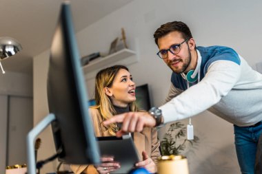 Genç çift evde bilgisayar ve dijital tablet üzerinde birlikte iş yapıyor..