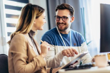 Başarılı genç çift, evde masada otururken bilgisayar başında birlikte çalışıyorlar.