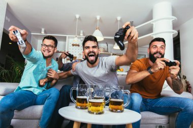 Arkadaşlık, teknoloji ve eğlence konsepti - evde oyun kağıtları ve bira ile gülen erkek arkadaşlar oyun oynuyorlar. 