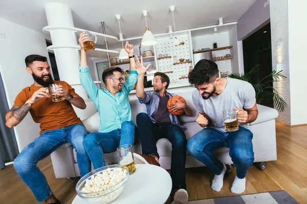 Heyecanlı basketbol hayranları TV maçı izleyip kanepede dinlenirken bağırıyorlar.
