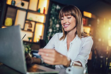 Kafeteryada oturan genç kadın ve online alışveriş yapmak
