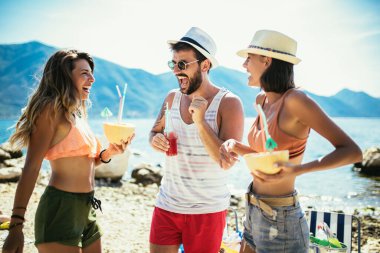 Bir grup arkadaş sahilde eğleniyor, dans ediyor ve kokteyl içiyor.. 