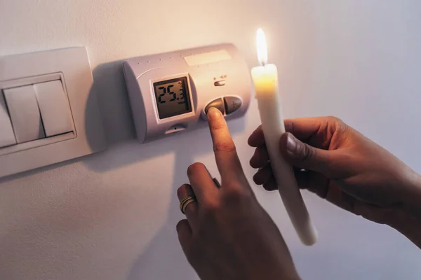 能源危机 完全黑暗中的人拿着蜡烛研究停电时的恒温器 停电的概念 — 图库照片