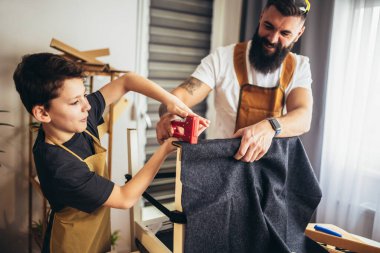 Gülümseyen baba oğluna evde döşemeyi öğretiyor, eğleniyor..