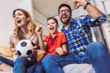 Taraftarların ailesi evde futbol maçı izliyor.