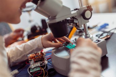 Çocuklar evde mikroskop kullanarak robot yapıyorlar. Evde robotik eğitimi.