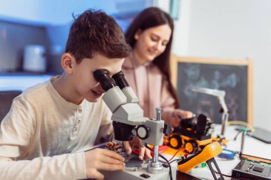 Çocuklar evde mikroskop kullanarak robot yapıyorlar. Evde robotik eğitimi.