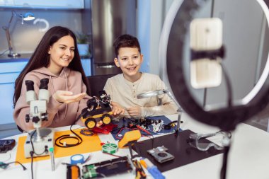 Erkek ve kız kardeş atölyede bir robot yapıp video kaydediyor..