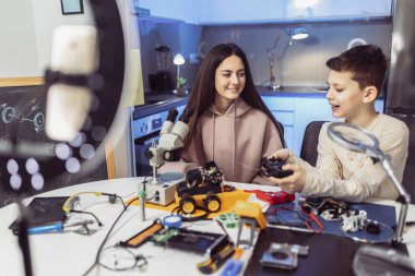 Erkek ve kız kardeş atölyede bir robot yapıp video kaydediyor..