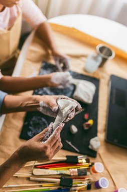 Anne ve kızı birlikte zaman geçirir ve evde kilden heykel yapıp çevrimiçi dersler izlerler.