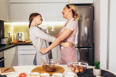 Anne ve kızı birlikte mutfakta yemek gülümseyen