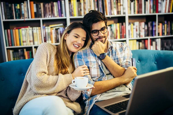Gözlüklü çekici bir adam ve kafede bir fincan kahveyle dizüstü bilgisayar kullanan çekici bir kadın..