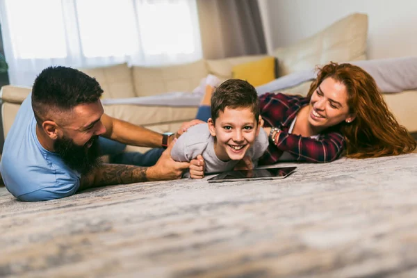 Šťastná Rodina Jedním Dítětem Leží Koberci Používání Digitálních Tabletu — Stock fotografie