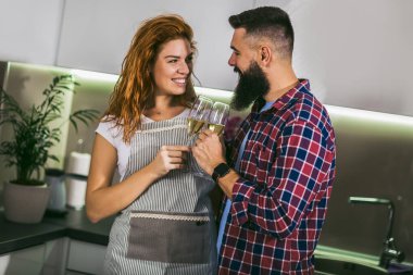 Aşık genç bir çift ev mutfağında şarap içiyor.